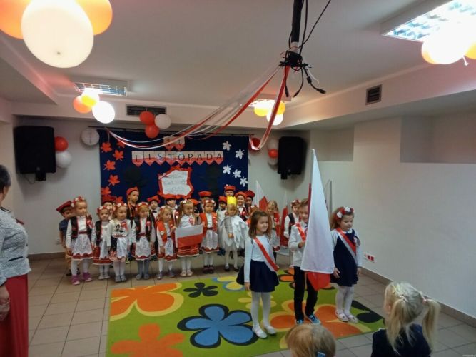 Dzieci stoją na baczność i śpiewają hymn polski
